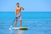 Fit man paddleboarding in turquoise sea