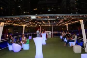 Guests enjoying the rooftop of a houseboat under fairy lights.