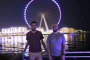 Two men posing with Ain Dubai in the background at night