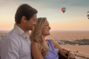 A couple enjoying a romantic hot air balloon ride at sunrise over the desert.