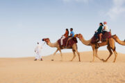 Couple enjoying a camel ride at sunset in the desert.