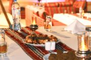 A candle-lit dinner setup with grilled meats, beverages, and Arabian décor