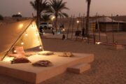 A luxury desert lounge with comfortable seating, soft lighting, and traditional Arabian tents.