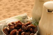 A bowl of dates with traditional Arabic coffee pots on a desert table.