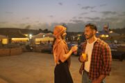 A couple enjoying drinks and conversation in a scenic desert camp during twiligh