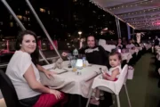 Guests enjoying dinner at sunset on a yacht with a view of the Dubai Ferris Wheel.