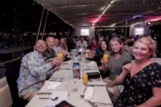 A group of friends smiling and raising glasses during a yacht dinner party