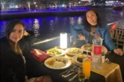 Two women enjoying a delicious dinner with marina night views.