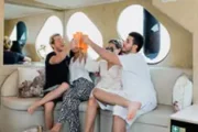 Friends toasting drinks on a luxury yacht interior.