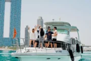 Group of people enjoying a party on the deck of a luxury yacht with Dubai's skyline in the background.