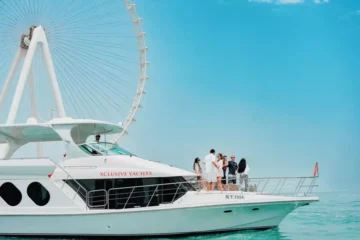 A white luxury yacht with a group of people against the backdrop of Dubai Marina's towering skyline.