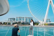 A woman posing for a photo near the Ain Dubai Ferris Wheel, captured from a luxury yacht.