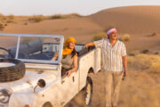 Couple by a vintage Land Rover in the desert.