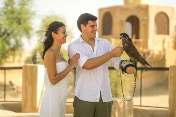 A couple enjoying a falconry experience in a serene desert setting.