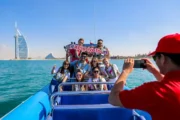 Group raising their hands in joy during a speedboat ride near Burj Al Arab.