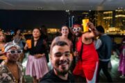 Guests enjoying a vibrant yacht party at night with the city skyline in the background.