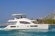 Exclusive Yachts catamaran cruising near a luxury waterfront residence