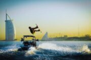 Man performing a wakeboarding flip in front of Burj Al Arab during sunset in Dubai.