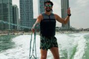 A man smiling while wakeboarding near Dubai's skyscrapers.