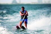 Person enjoying water skiing with banana boats and kayaks in the background