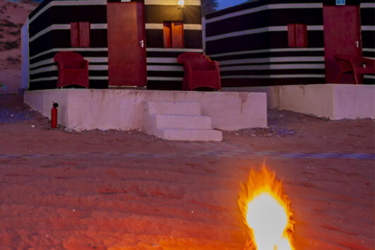 Close-up of desert campsite firepit with private tents in the background.