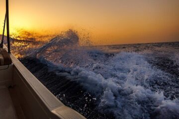 Ocean waves crashing at sunset from a boat.