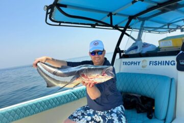 Man holding a large fish on a fishing boat with 