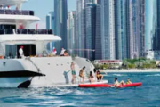 Guests enjoying water activities near a luxury yacht with Dubai skyline in the background.