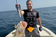 Excited fisherman presenting a grouper caught during a thrilling fishing adventure.