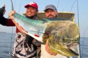 Two fishermen holding a large Mahi-Mahi fish