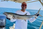 Smiling fisherman with a Kingfish on a fishing tour.