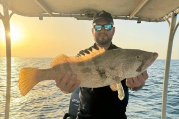 Angler holding a large fish during a scenic sunset fishing trip