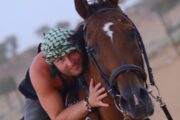 A man affectionately hugging his horse in a desert setting.