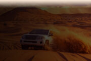 4×4 vehicle kicking up sand while dune bashing in a desert landscape.