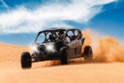 Black CAN-AM Maverick dune buggy speeding through desert sand dunes.