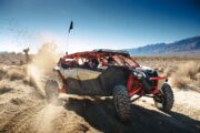 A Can-Am Maverick X3 dune buggy drifting in the desert.