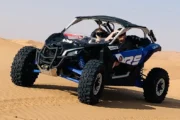 A rider in a buggy while ATVs follow in the background