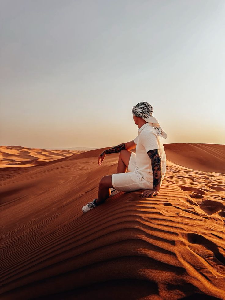 Man sitting on sand dunes at sunset in the desert