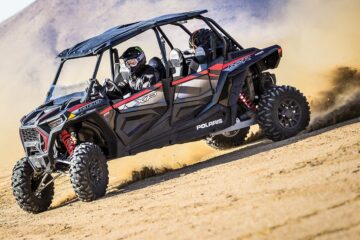 A black Polaris RZR XP 4-seater buggy speeding down the sand dunes.