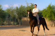 A woman riding a horse through a scenic desert landscape.