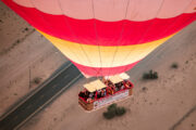 A vibrant red and yellow hot air balloon floating above the desert.