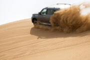 4x4 SUV kicking up sand during a dune-bashing adventure.