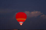 A red and yellow hot air balloon illuminated against the twilight sky.