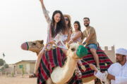 A group of tourists enjoying a camel ride in the desert, led by a local guide.