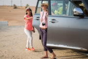 Happy tourists stepping out of an SUV in the desert, ready for an adventure.