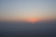 A golden sunrise peeking through the hazy desert horizon.