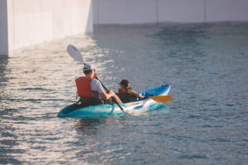 Two people kayaking through lush mangrove waters.