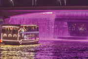 Dubai canal cruise under a stunning illuminated waterfall