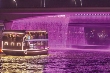 Dubai canal cruise under a stunning illuminated waterfall