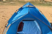 A single blue camping tent in the desert, showing the sleeping area inside.